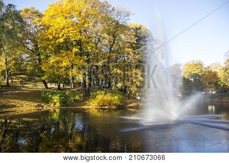 Fountain and rainbow in Riga Canal that flows through Bastion park autumn background with colored leaves (Bastejkalns). Latvia autumn