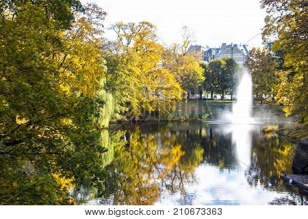 Fountain and rainbow in Riga Canal that flows through Bastion park autumn background with colored leaves (Bastejkalns). Latvia autumn