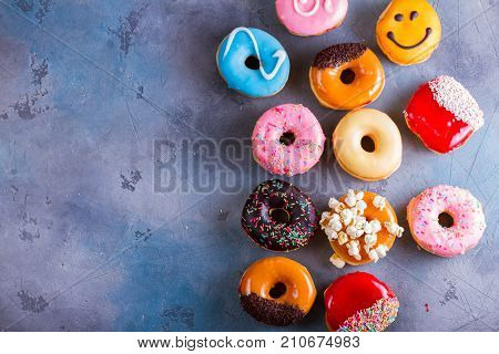 sweet doughnuts flat lay border on gray stone background with copy space