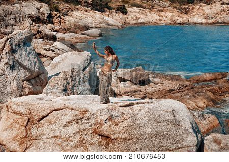 tribal woman belly dancer dancing on stone beach