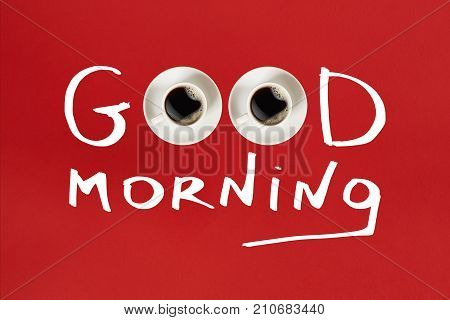 Close-up top view of cup of fresh hot coffee and good morning inscription on red background. Still life. Mock up. Flat lay