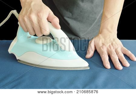 man pressing blue automatic electric iron to shirt on ironing board