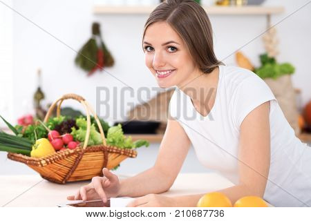 Young woman is making online shopping by tablet computer and credit card. Housewife found new recipe for  cooking in a kitchen