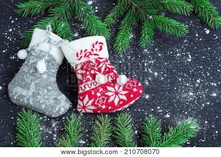 Two Christmas Stockings On Snowbound Black Background With Fir Branches