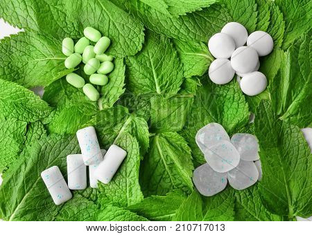 Different hard candies and chewing gum on mint leaves