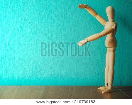 Wooden puppet show hands holding the blank sign. Wooden puppet stand on the wooden table. the background is turquoise and copy space for content.