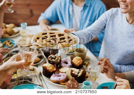 Woman offering tasty sweet pie with jam to one of guests by festive tavle
