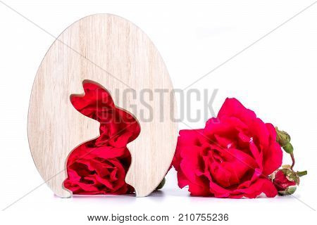 close-up of wooden easter egg with rabbit shape of rose flowers in background. template with copy space. easter concept and easter greeting card.