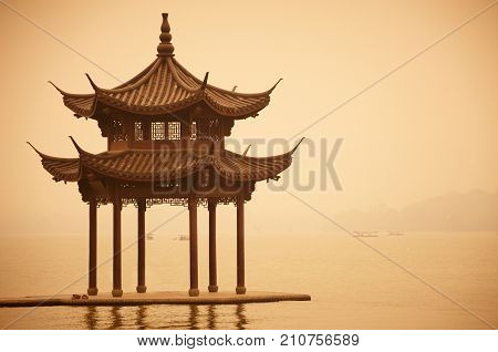 Chinese traditional wooden gazebo on the coast of West Lake, public park in Hangzhou city, China.