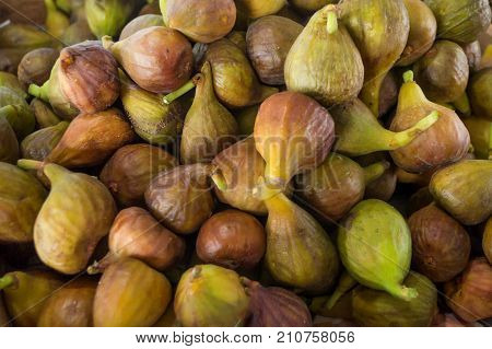 Brown and green figs in the market as a background