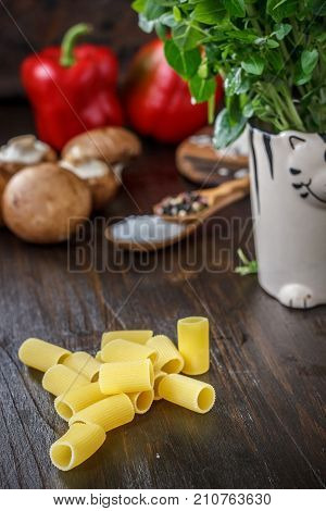 Bazil and pasta over brown wooden table on kitchen
