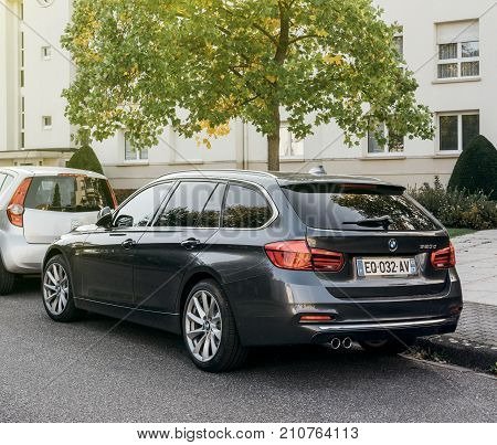 STRASBOURG FRANCE - SEP 24 2017: Rear view of BMW 320d wagon luxury car parked on a city street with beautiful sun flare