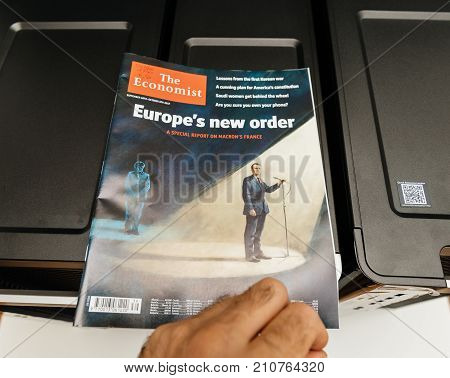 PARIS FRANCE - OCT 20 2017: Man reading The Economist magazine with illustration of Emmanuel macron and A Merkel and Europe's new order