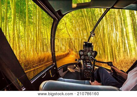 Helicopter cockpit inside the cabin flying in surreal bamboo grove at Sagano in Arashiyama, sunlit. Asian travel destination. Exploration and adventure concept.