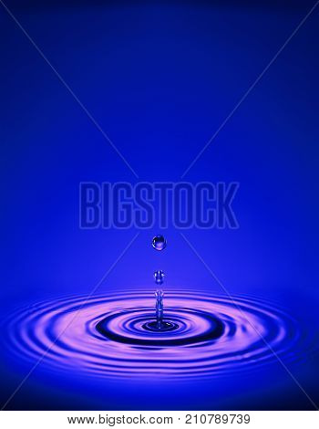 WATER DROPLET MAKING RIPPLES IN COLOURED LIQUID