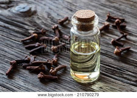 A Bottle Of Clove Essential Oil With Dried Cloves On A Wooden Background