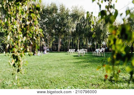 Place for wedding ceremony with white chairs and an arch of living plants