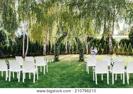 Place for wedding ceremony with white chairs and an arch of living plants