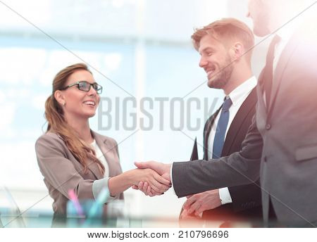 Happy smiling business people shaking hands after a deal in offi