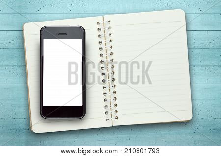 Blank screen phone on book in wooden background.Photo with copy space.