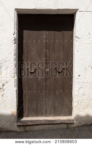 old wooden door with iron door handles at noon in direkt sunlight