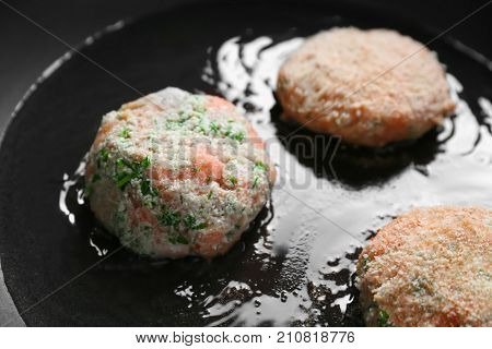 Salmon patties frying on pan, closeup
