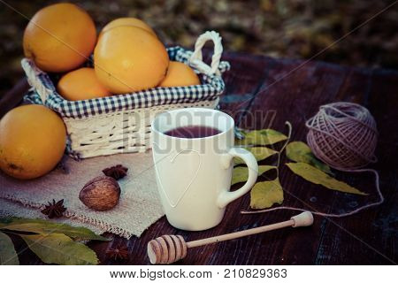 tea with lemon, honey, oranges, autumn leaves on woodenbackground