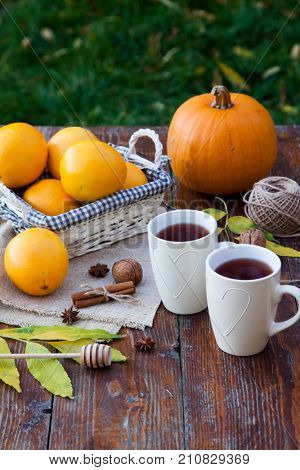 tea with lemon, honey, oranges, autumn leaves on woodenbackground