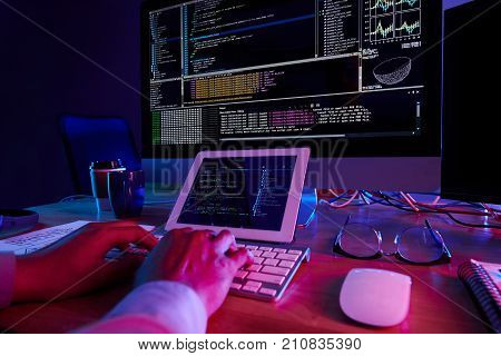 Back-end developer working on code in dark office