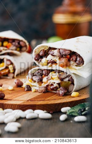 Nice vegetarian burrito over black table on wooden board