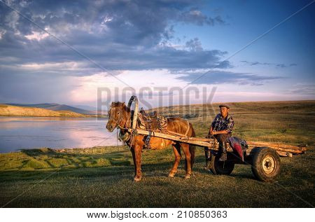 Horse man sitting on a horse cart in a scenic view of nature.