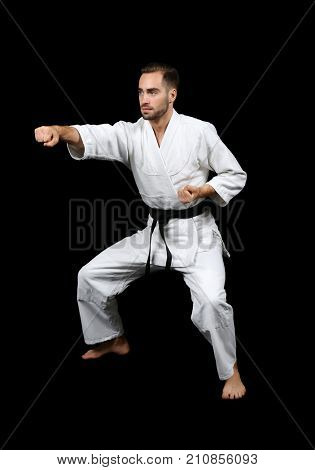 Young man practicing karate on dark background