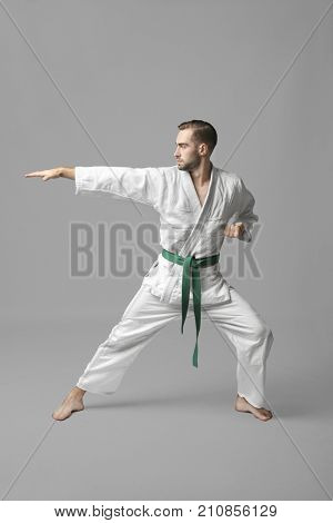 Young man practicing karate on light background