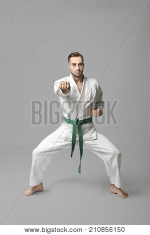 Young man practicing karate on light background
