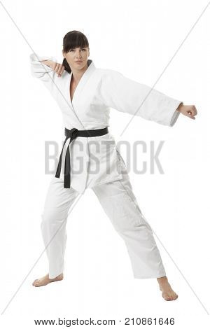 Young woman practicing karate on white background