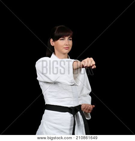 Young woman practicing karate on dark background