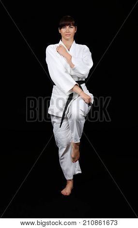 Young woman practicing karate on dark background