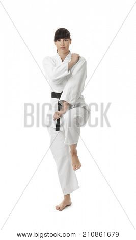 Young woman practicing karate on white background