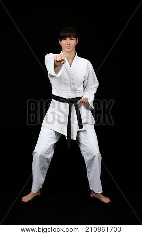 Young woman practicing karate on dark background