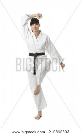 Young woman practicing karate on white background