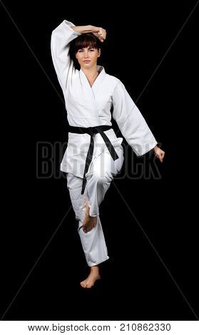 Young woman practicing karate on dark background
