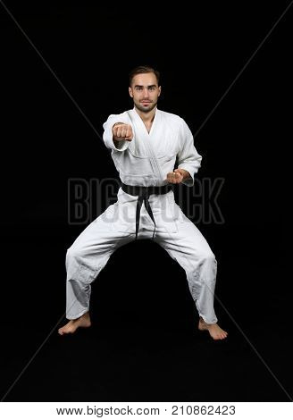 Young man practicing karate on dark background