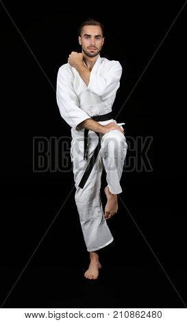 Young man practicing karate on dark background