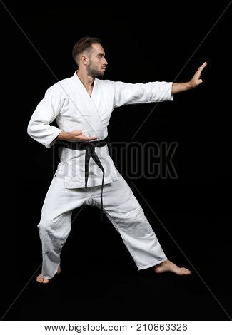 Young man practicing karate on dark background