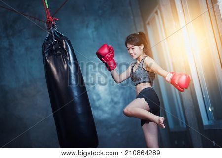 sexy asia girl punching boxing bag at the gym