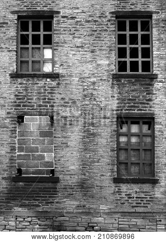 four broken and bricked up windows in a derelict abandoned old house with dirty stained bricks