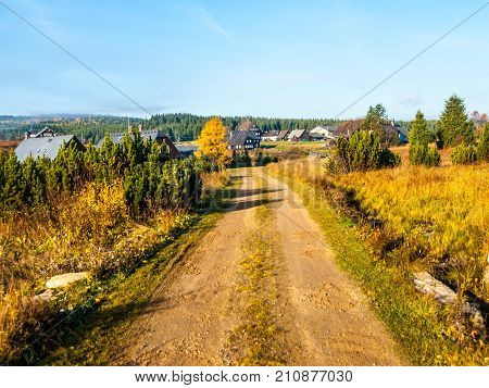 Country road in Jizerka village on sunny autumn day, Jizera Mountains, Czech Republic.