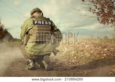 Photographer in war conflict field zone preparing for shooting