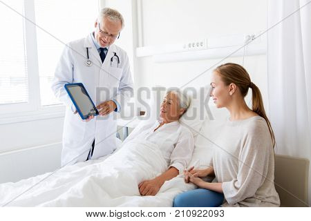 medicine, healthcare and people concept - senior woman patient with daughter and doctor with tablet pc computer at hospital ward