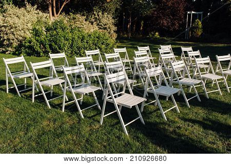 Place for wedding ceremony with white chairs and an arch of living plants